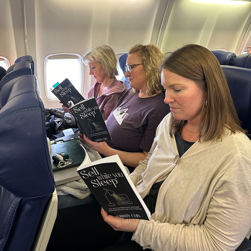 Author Krissy Chin reading the book Sell while you Sleep on a plane